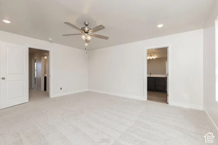 Unfurnished bedroom featuring light carpet, a ceiling fan, recessed lighting, and connected bathroom