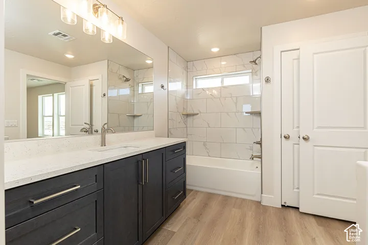 Bathroom with vanity, bathing tub / shower combination, light wood finished floors, and recessed lighting