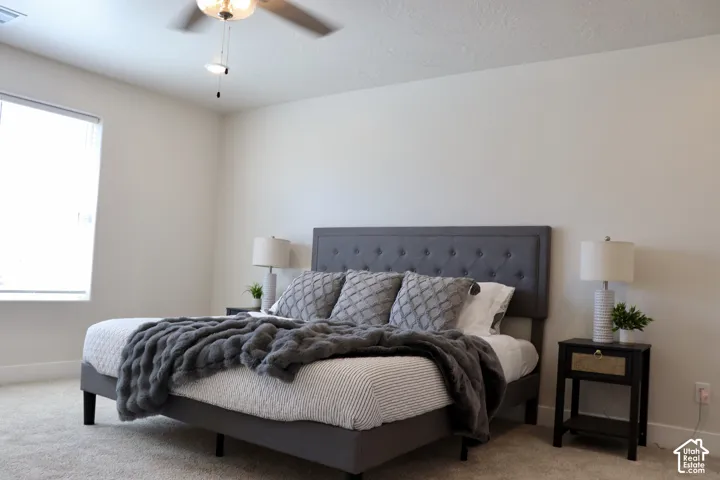 Spacious room featuring neutral carpeting, light-colored walls, and a ceiling fan with integrated lighting