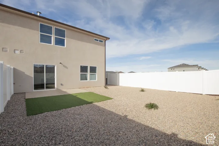 Rear view of house featuring a fenced backyard, stucco siding, and a patio