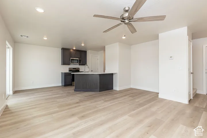 Unfurnished living room featuring a ceiling fan, light wood finished floors, and recessed lighting