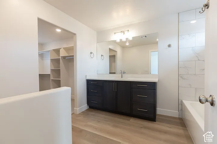 Bathroom featuring vanity, a spacious closet, light wood finished floors, and shower / bath combination