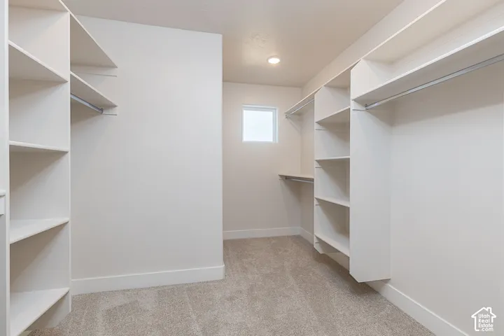 Walk in closet with light colored carpet