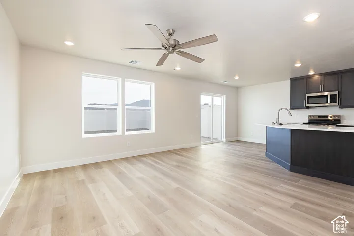 Kitchen with light wood-style floors, stainless steel appliances, a ceiling fan, recessed lighting, and open floor plan