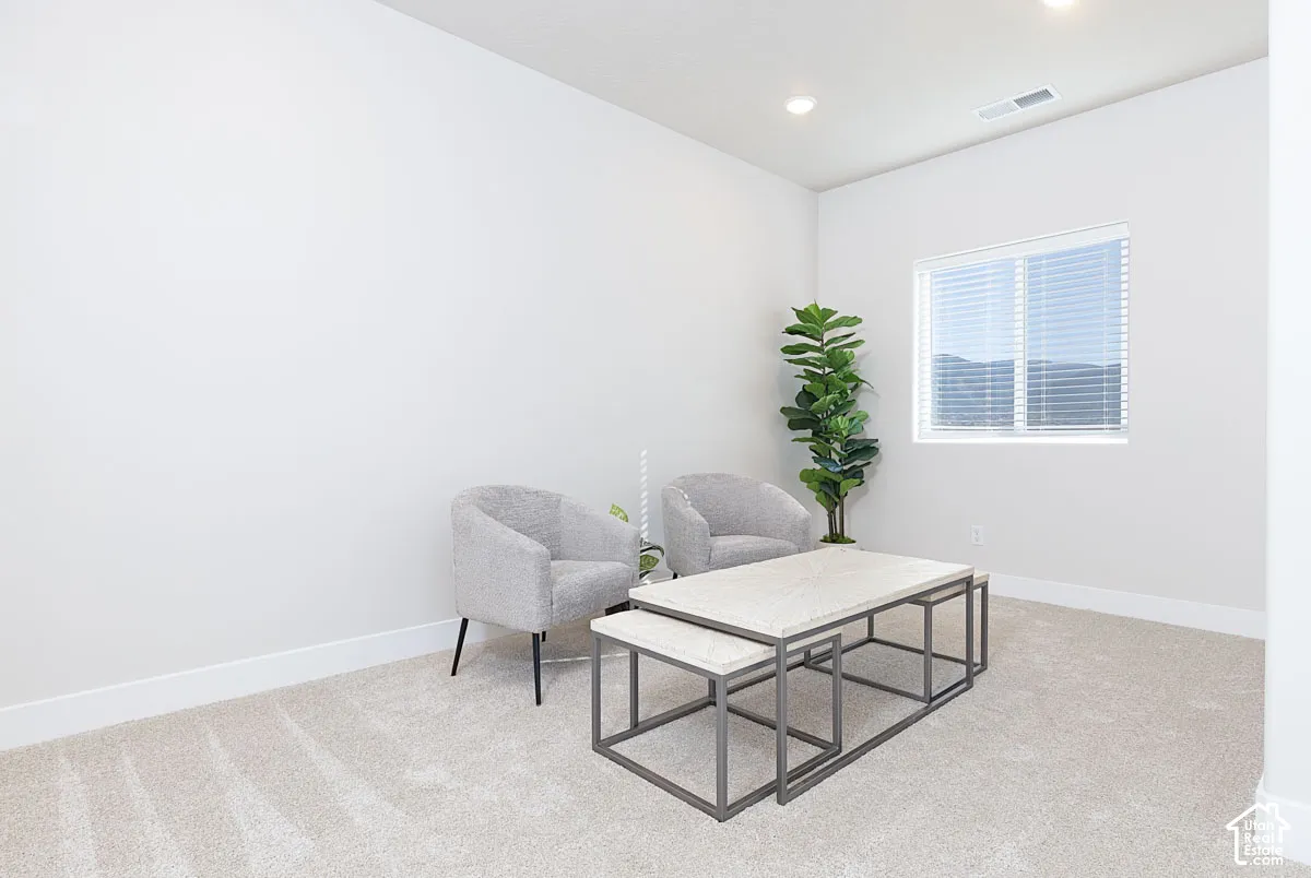 Living area with light carpet and recessed lighting