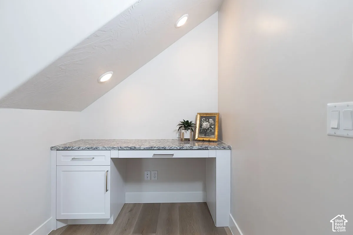 Detailed view of built in desk, wood finished floors, and recessed lighting