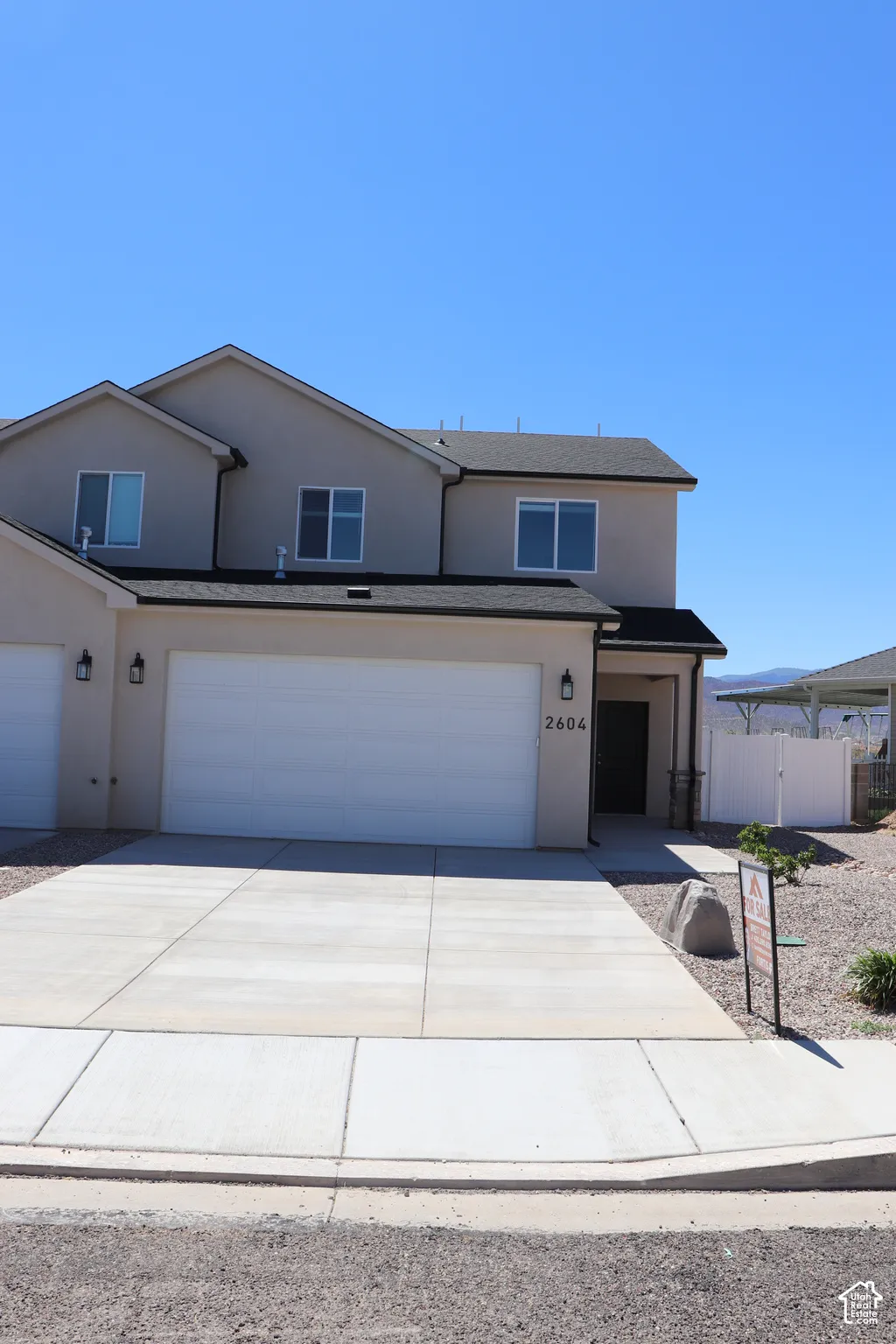 Contemporary multi-level residence featuring stucco exterior, dark trim, and a two-car garage