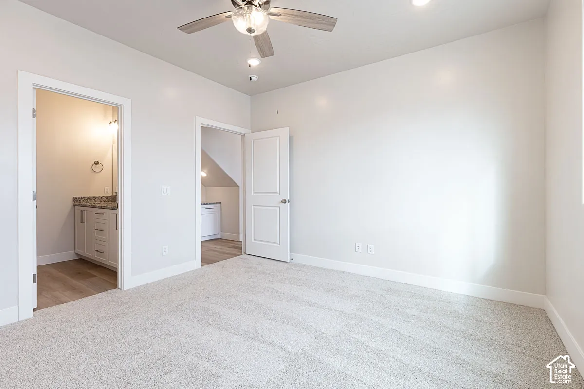 Unfurnished bedroom featuring light colored carpet, ensuite bath, ceiling fan, and recessed lighting