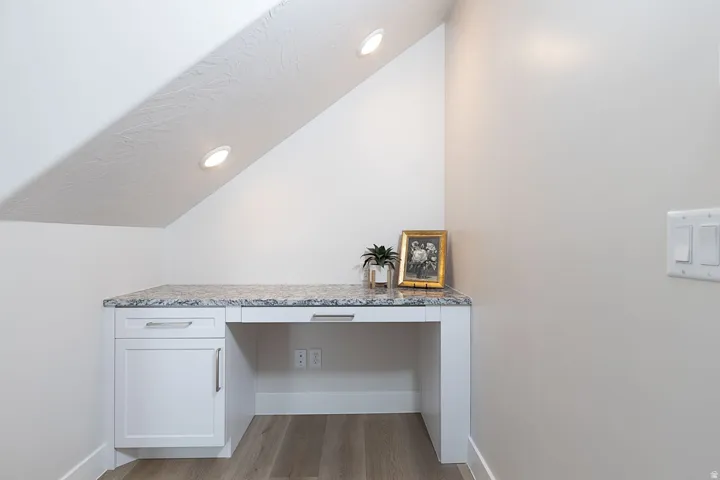 Detailed view of built in desk, wood finished floors, and recessed lighting