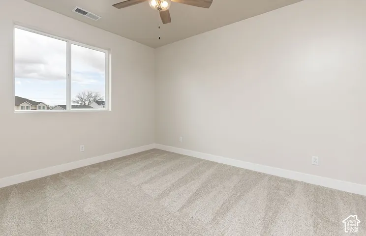 Empty room with light carpet and ceiling fan