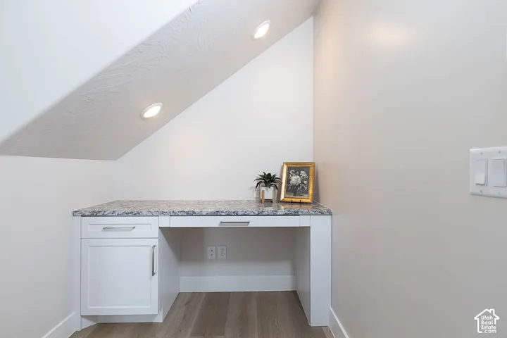 Detailed view of built in desk, wood finished floors, and recessed lighting