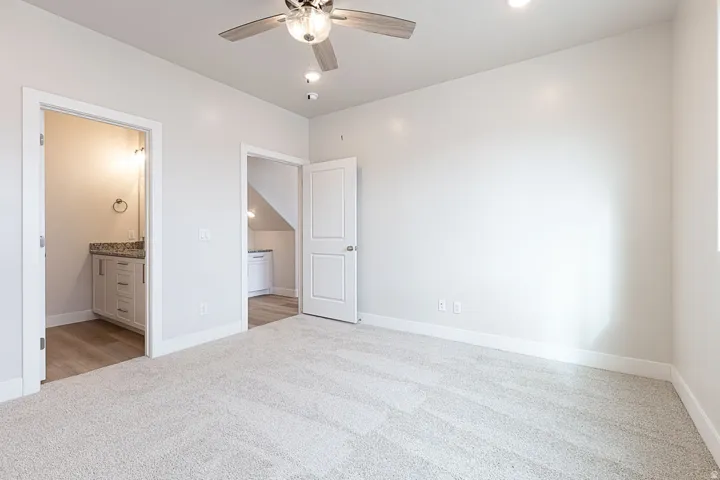Unfurnished bedroom featuring light colored carpet, ensuite bath, ceiling fan, and recessed lighting