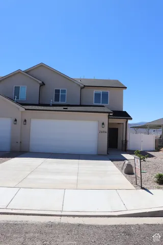 Contemporary multi-level residence featuring stucco exterior, dark trim, and a two-car garage