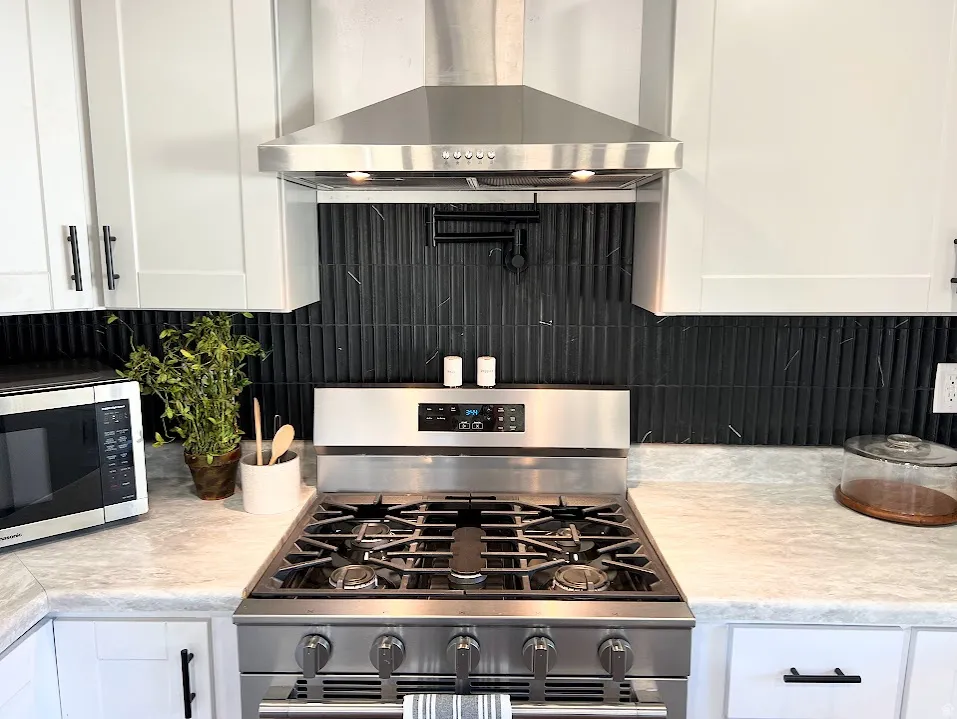 Kitchen with stainless steel appliances, light countertops, white cabinets, and tasteful backsplash