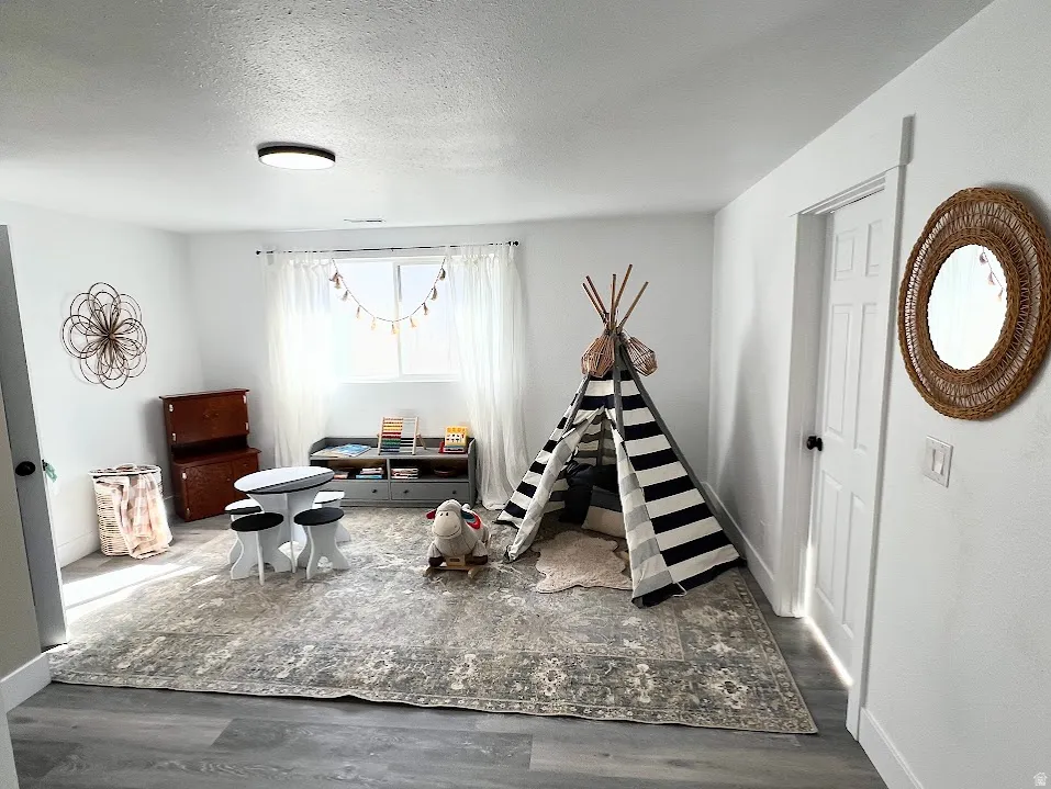 Playroom with dark wood-style flooring and a textured ceiling
