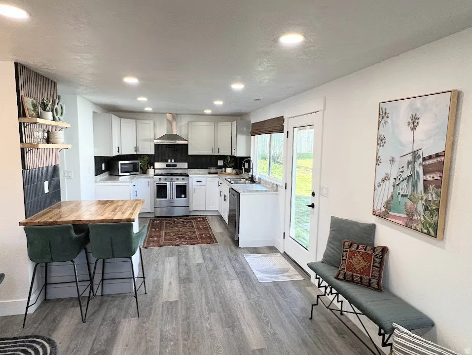Kitchen featuring stainless steel appliances, butcher block countertops, open shelves, light wood finished floors, and white cabinets