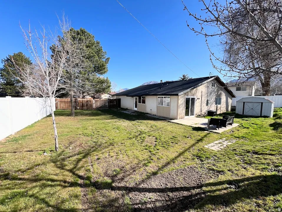 Rear view of property with a storage shed, a patio area, and a fenced backyard