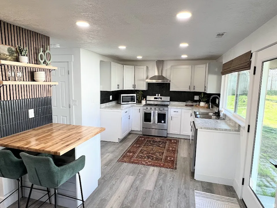 Kitchen featuring wooden counters, stainless steel appliances, recessed lighting, white cabinetry, and a kitchen bar