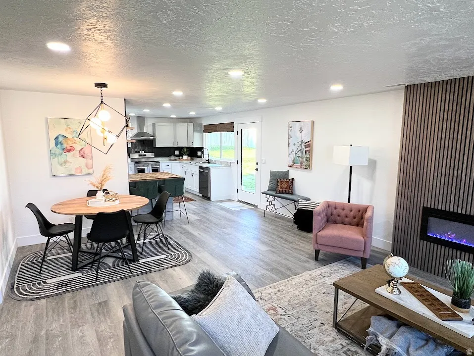 Living room with a textured ceiling, recessed lighting, light wood finished floors, and a glass covered fireplace