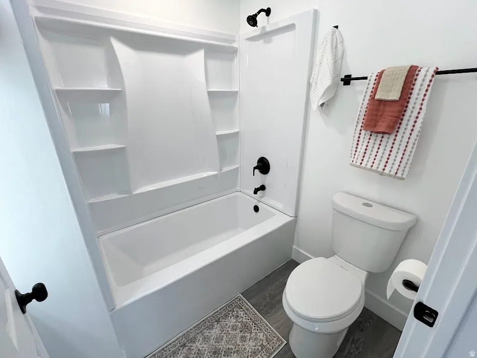 Bathroom with dark wood finished floors and shower / bath combination