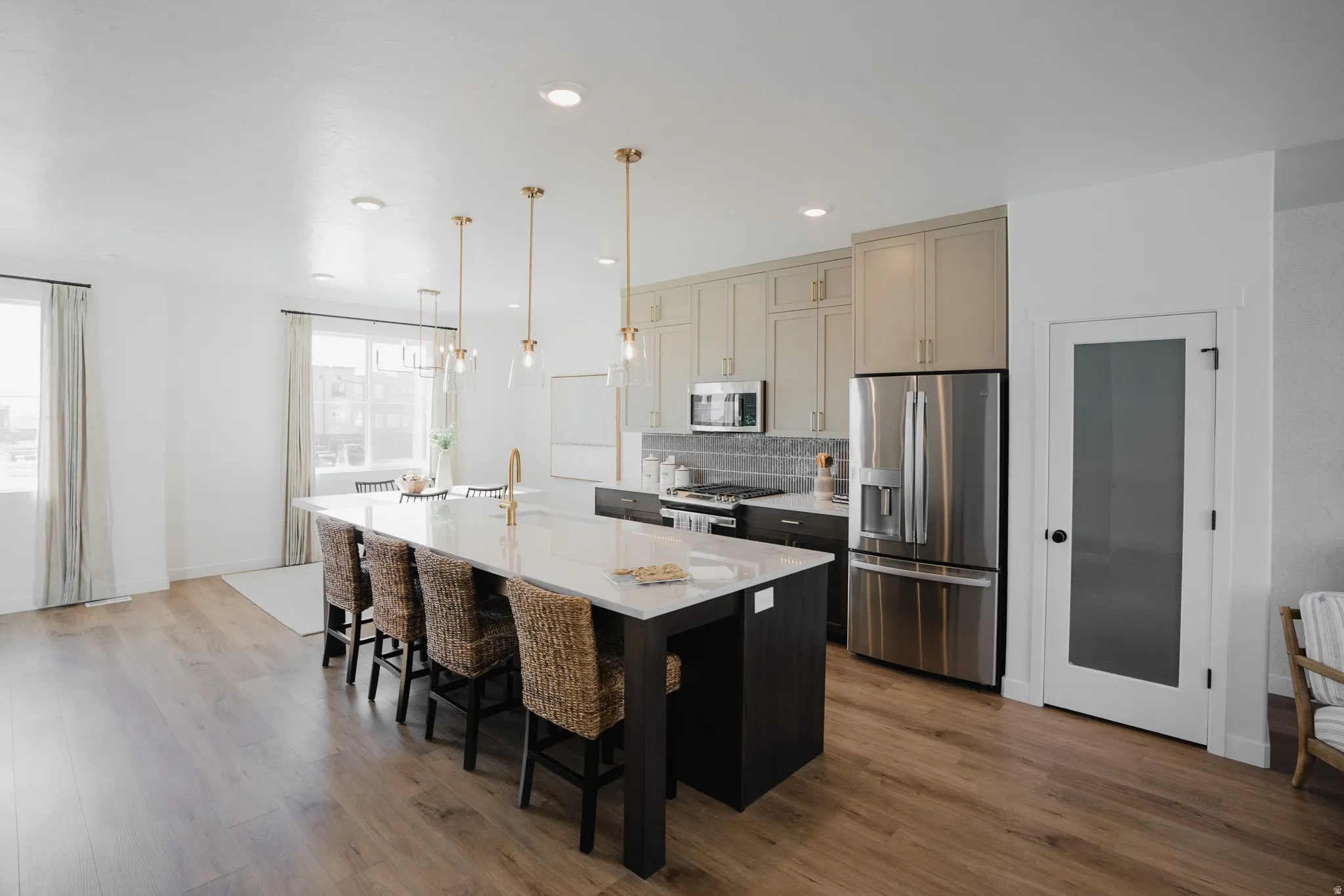 Kitchen with stainless steel appliances, a kitchen island with sink, dark wood-style floors, light stone countertops, and a kitchen bar