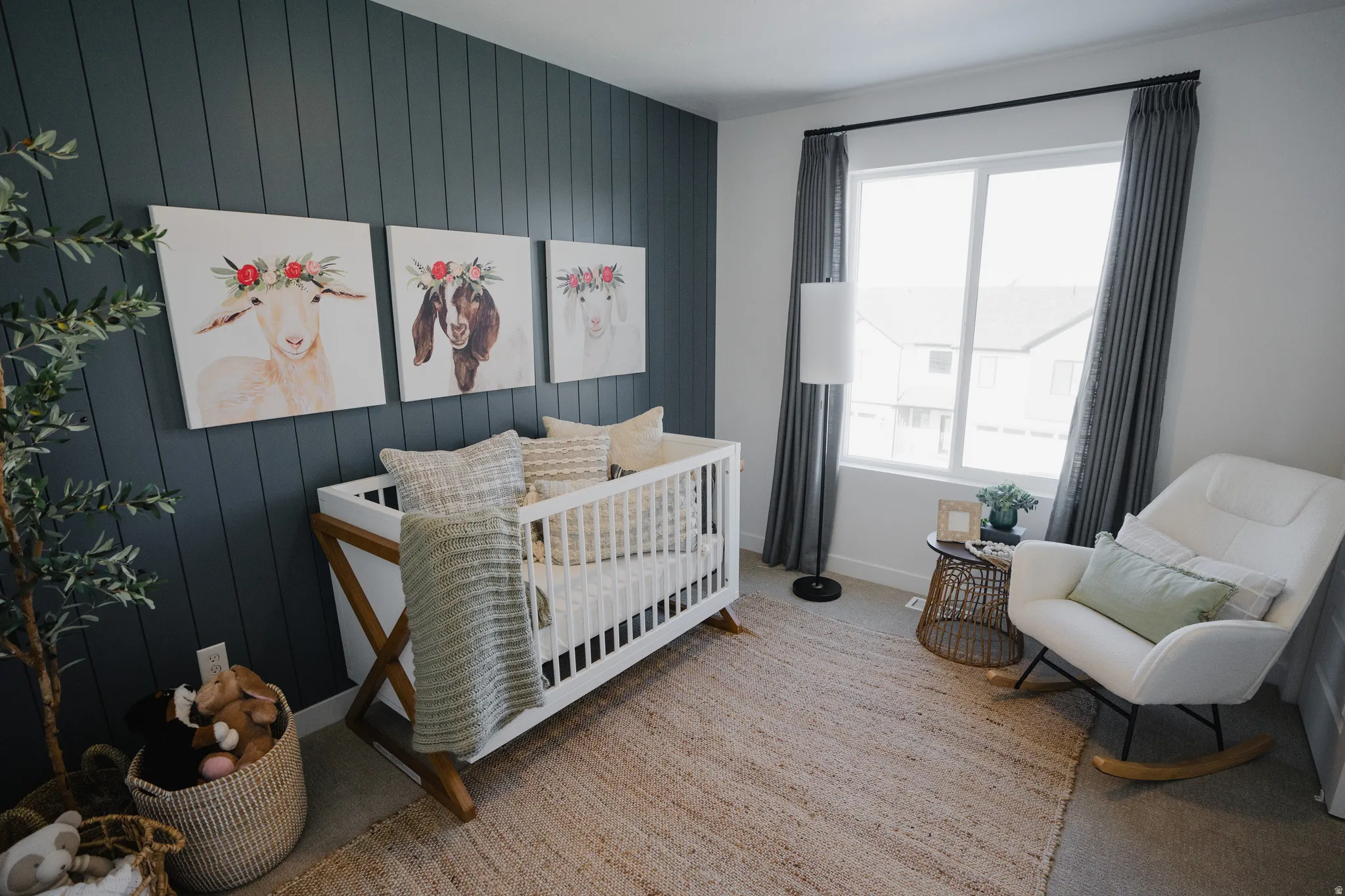 Bedroom featuring wooden walls, a crib, light carpet, and an accent wall