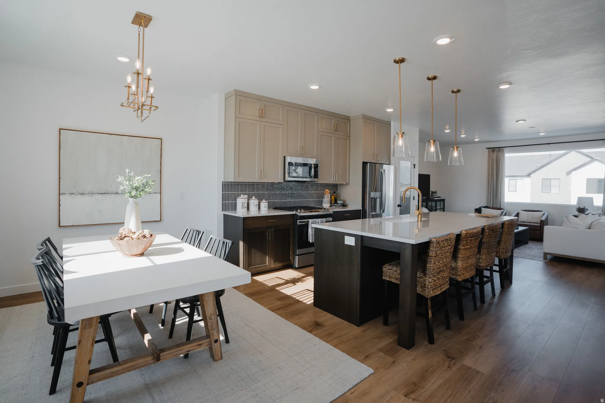 Kitchen with a center island with sink, stainless steel appliances, a kitchen breakfast bar, light wood-type flooring, and two tone cabinets