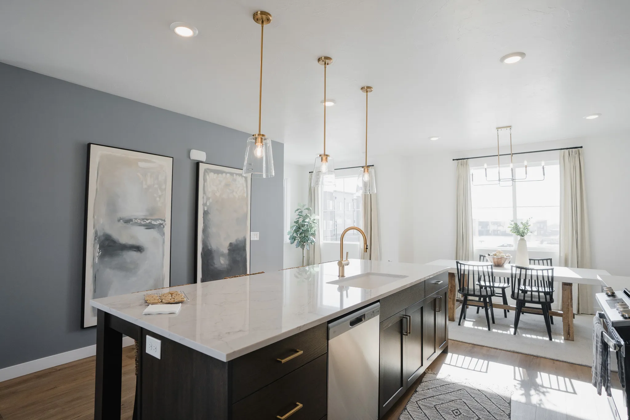 Kitchen featuring hanging light fixtures, dark wood-type flooring, stainless steel dishwasher, range, and light stone counters