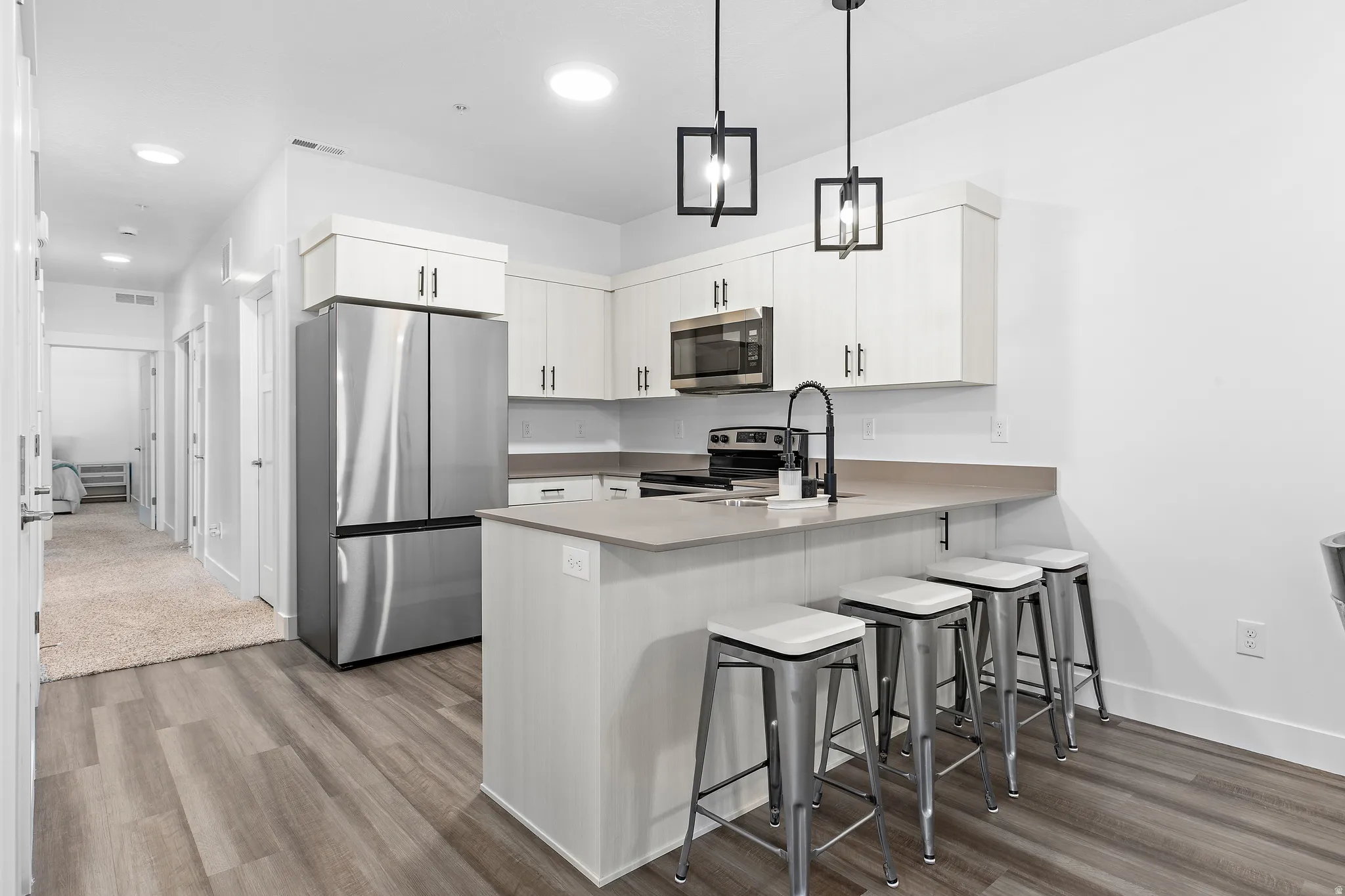 Kitchen with stainless steel appliances, a kitchen breakfast bar, light wood finished floors, and a peninsula