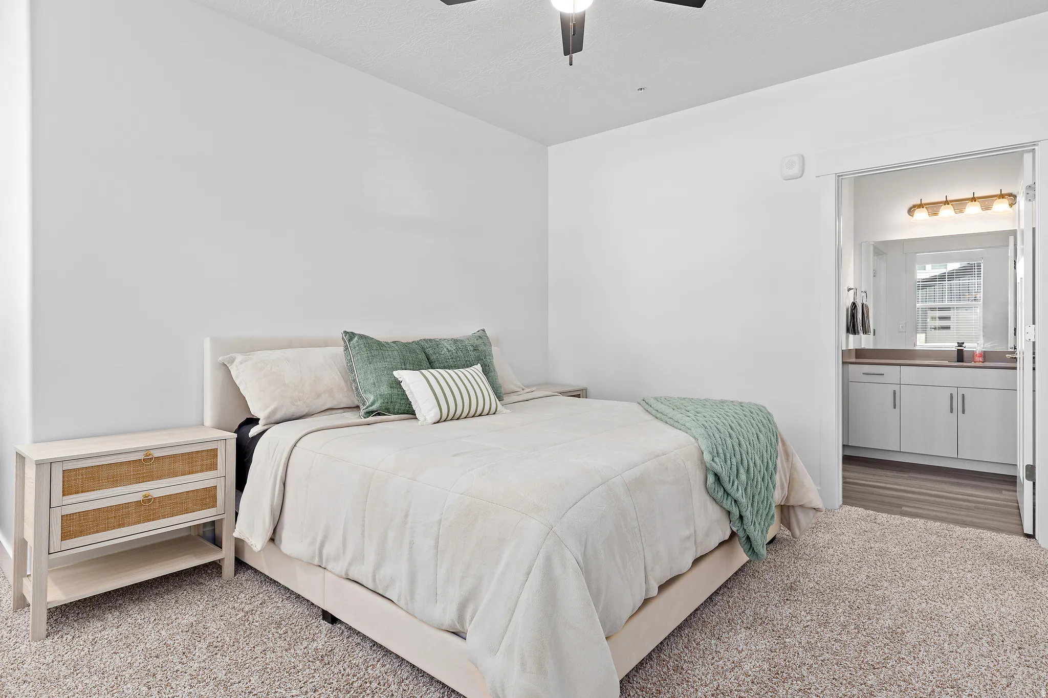 Carpeted bedroom with connected bathroom and a ceiling fan