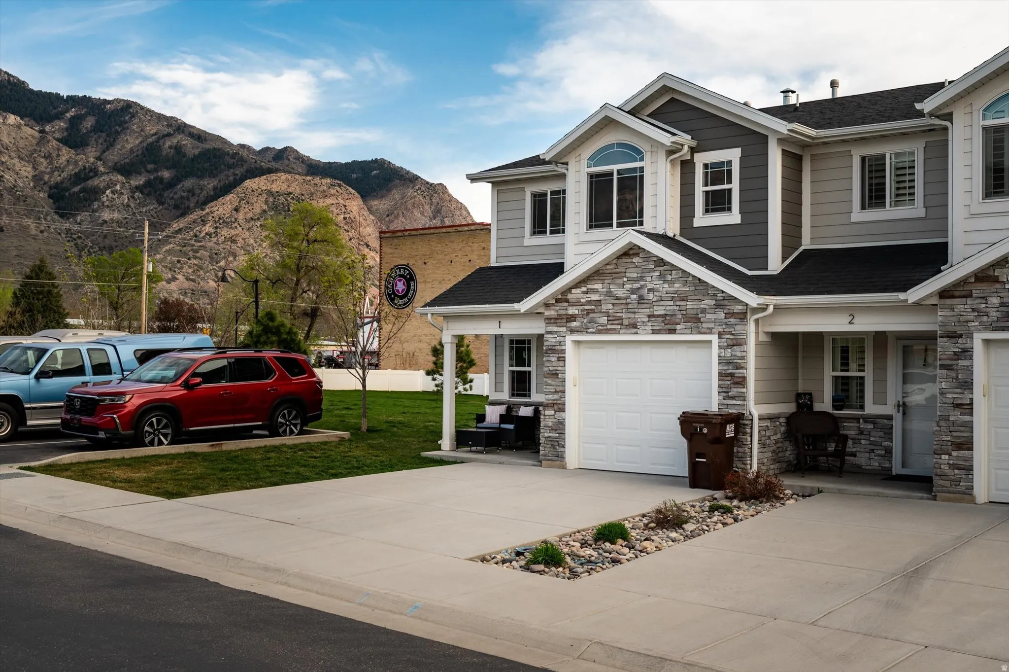 View of front of home with a front lawn, stone siding, a mountain view, and a shingled roof.