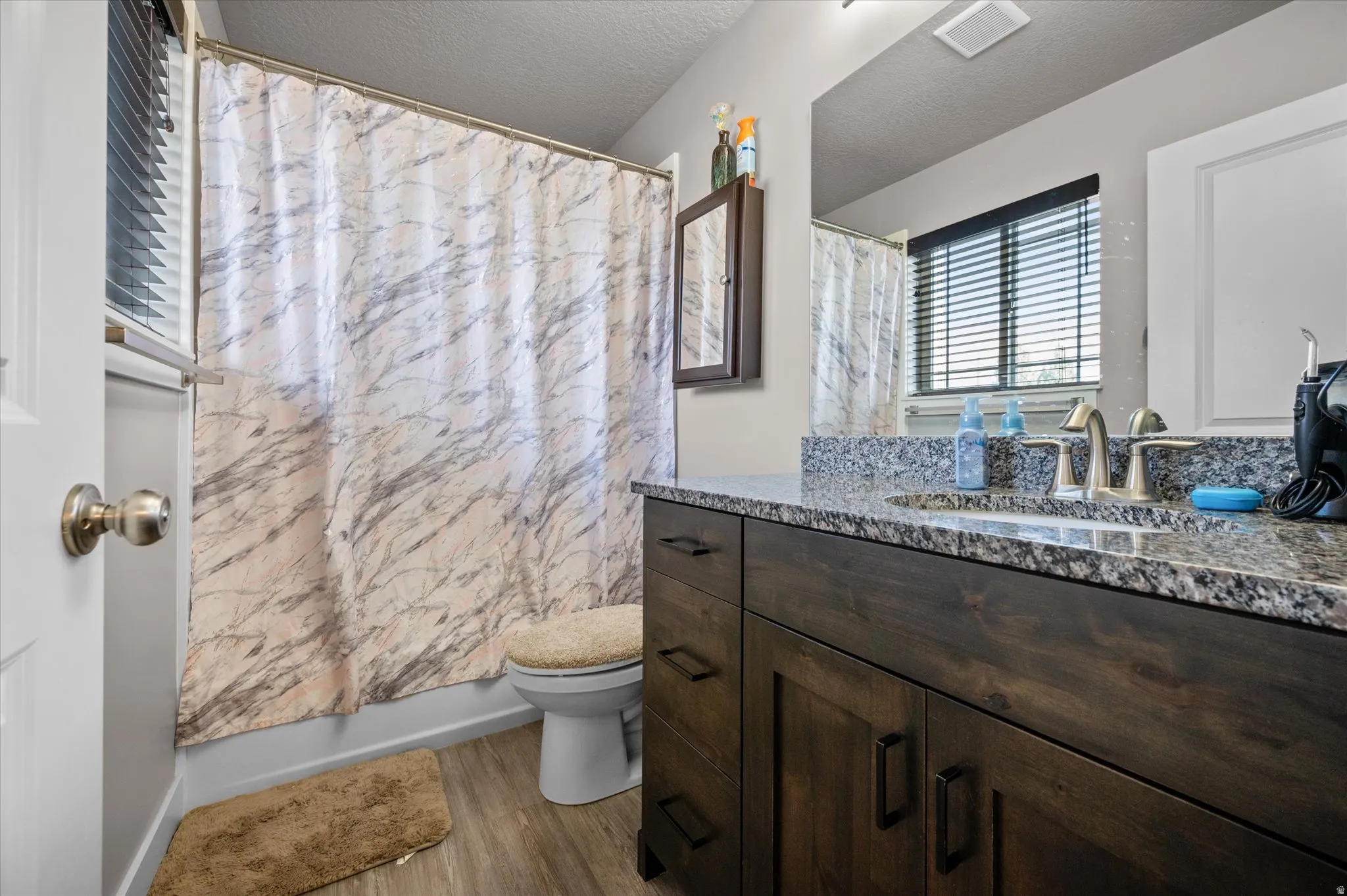 Bathroom with granite vanity, hardwood cabinetry, and full tub/shower.