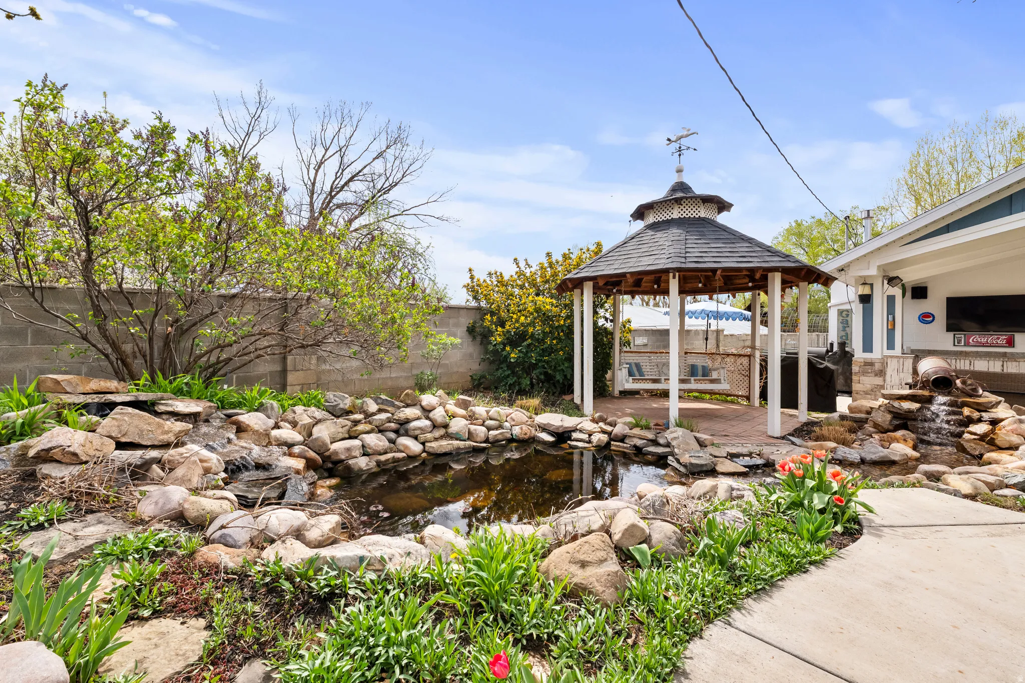 Fenced backyard featuring a small pond, a patio, and a gazebo