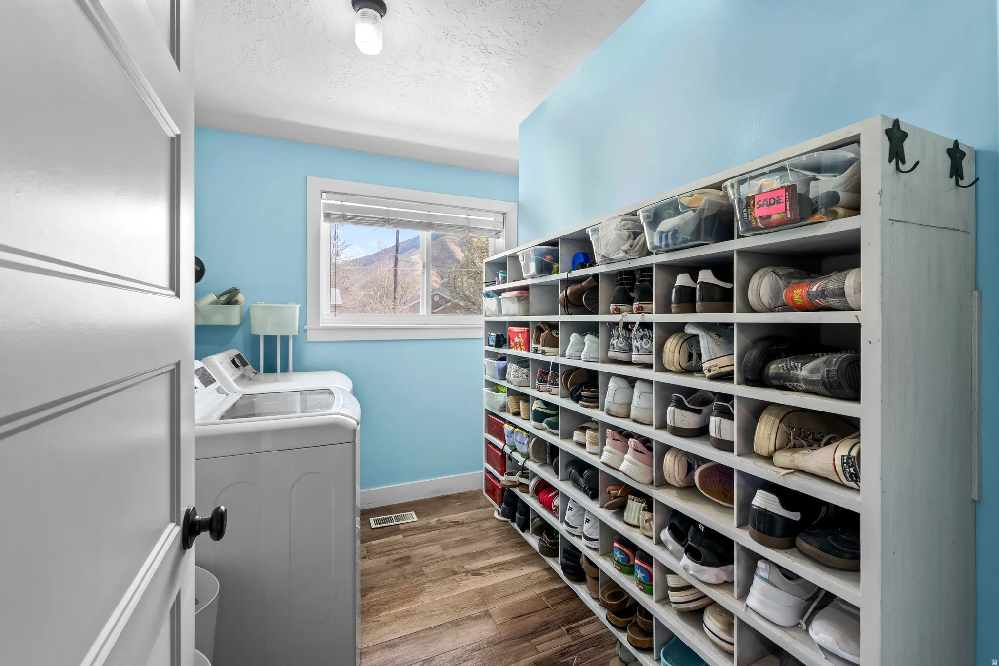 Laundry area with a textured ceiling, light wood-style floors, and washing machine and dryer