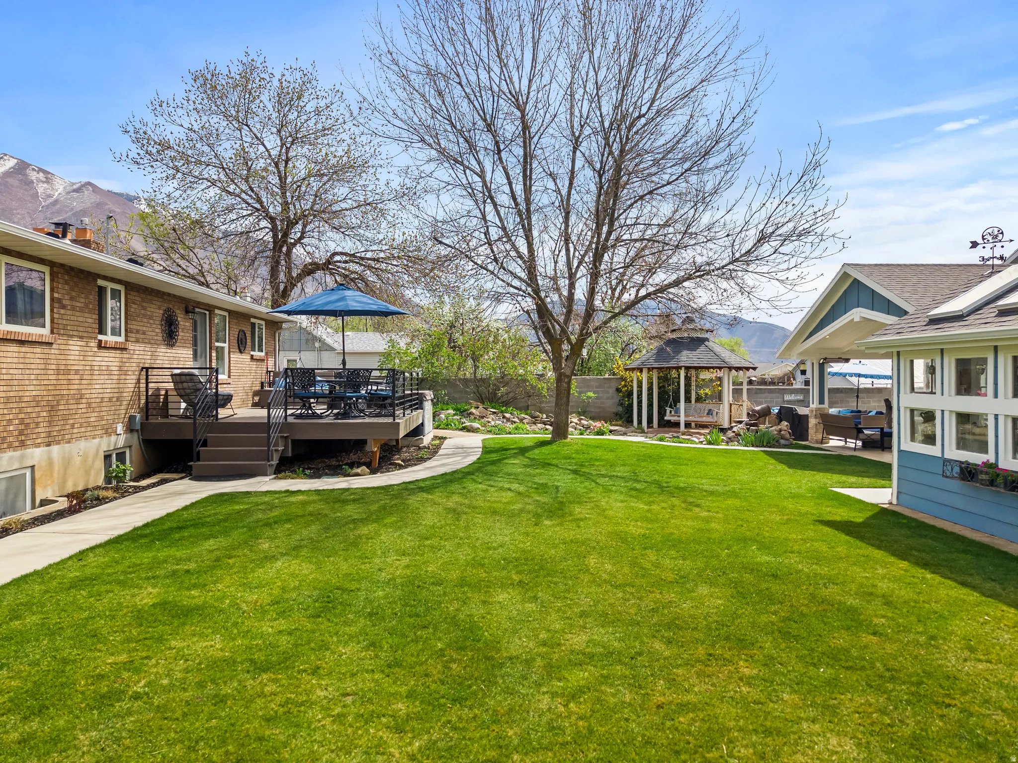 Fenced yard featuring a deck with mountain view, a gazebo, and a patio