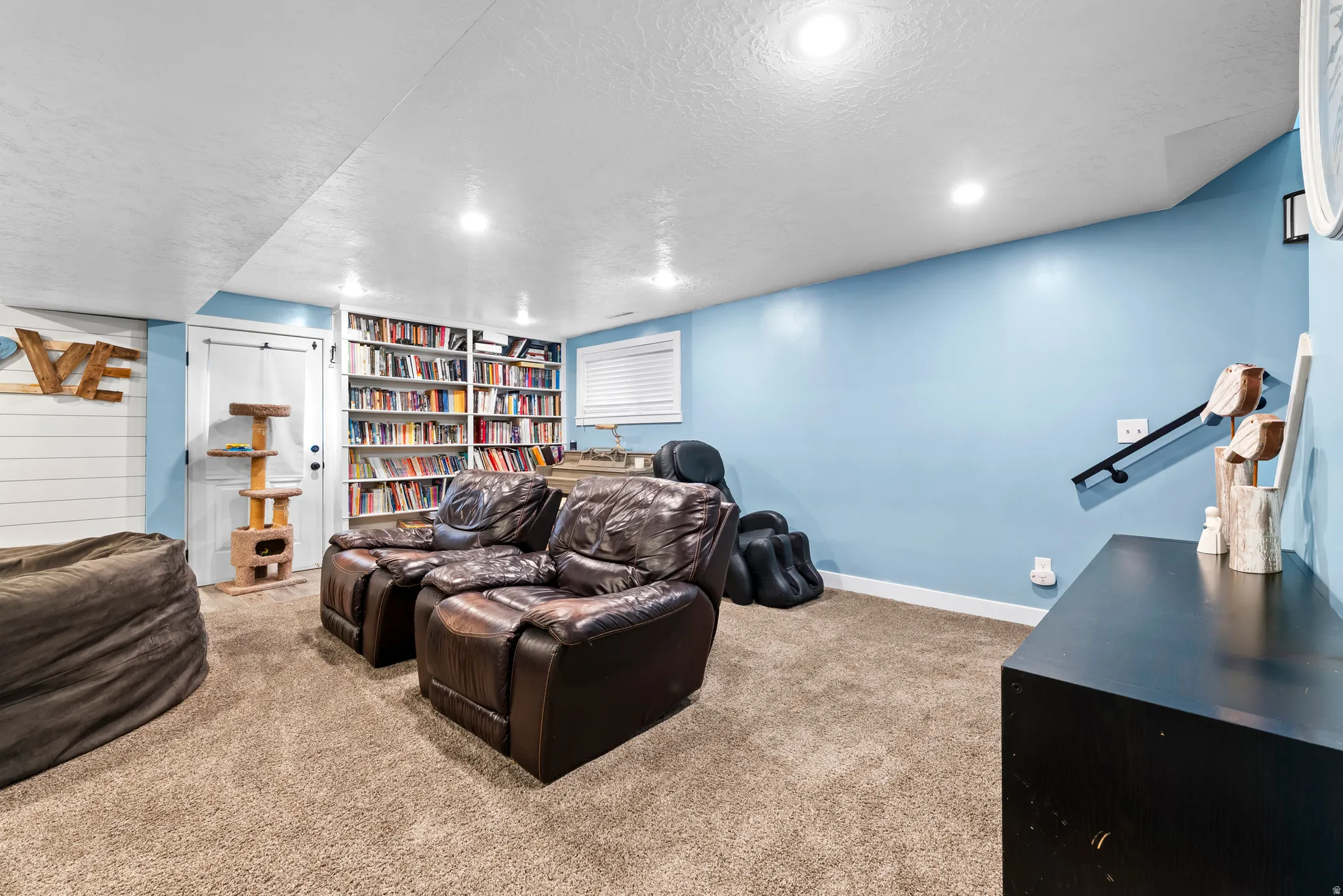 Cinema room featuring light carpet, a textured ceiling, and built in shelves