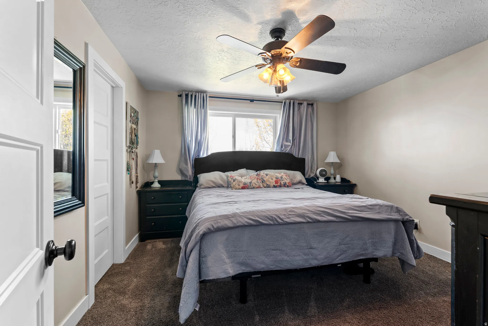 Bedroom featuring a ceiling fan, dark carpet, and a textured ceiling