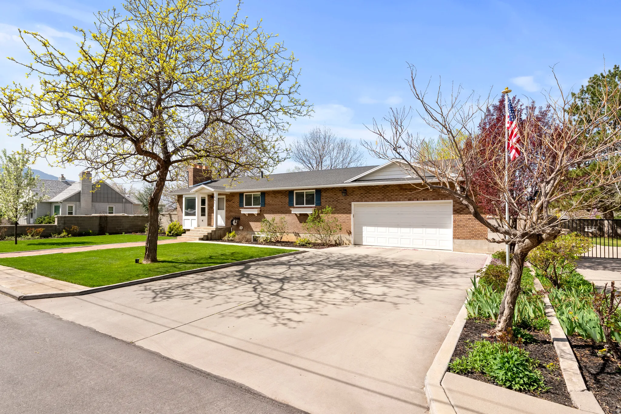Single story home featuring driveway, a garage, brick siding, and a chimney