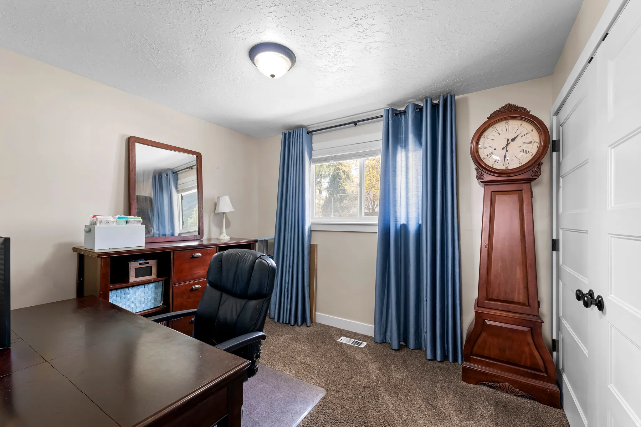 Home office featuring dark colored carpet and a textured ceiling