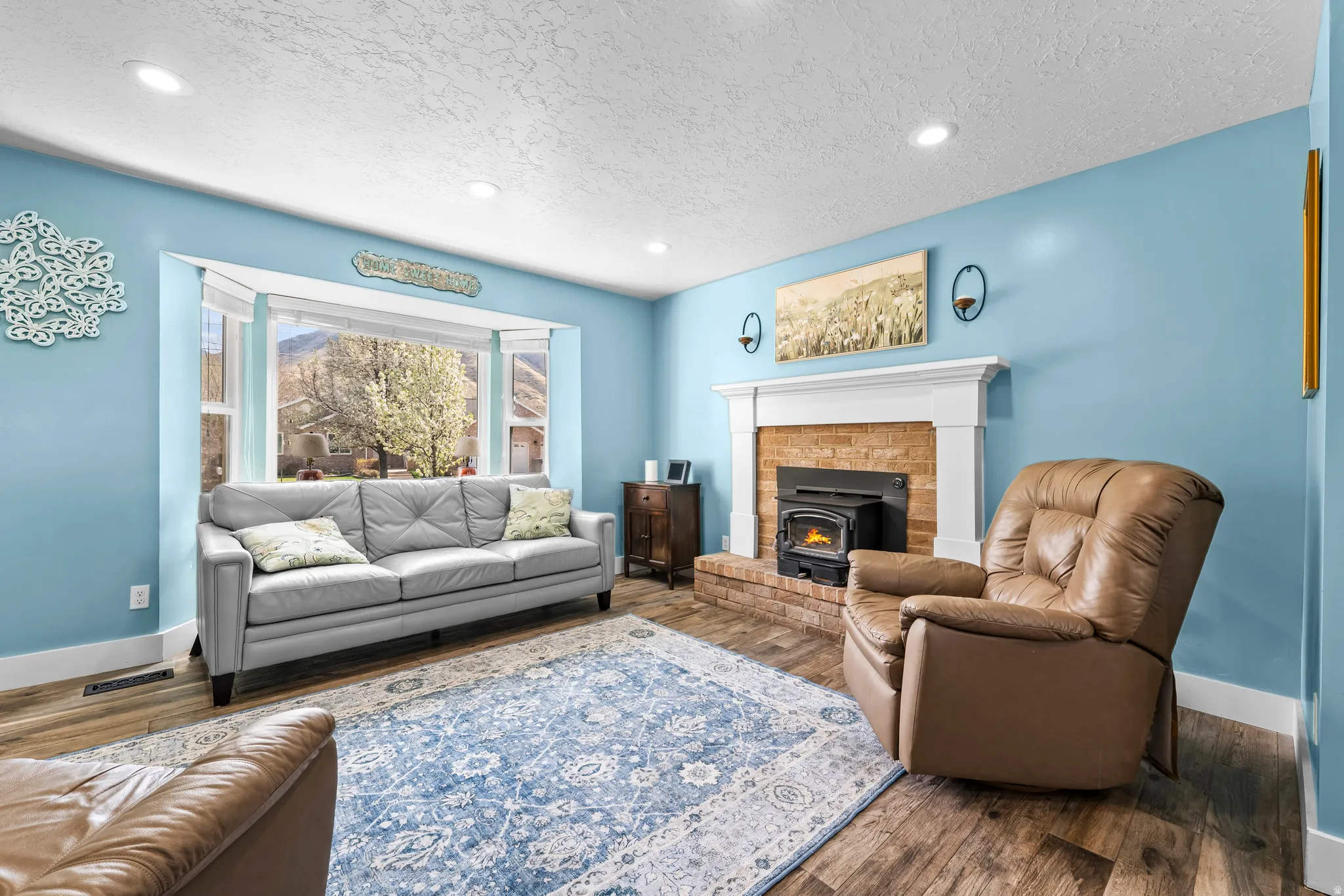 Living room featuring wood finished floors, a textured ceiling, recessed lighting, and a wood stove