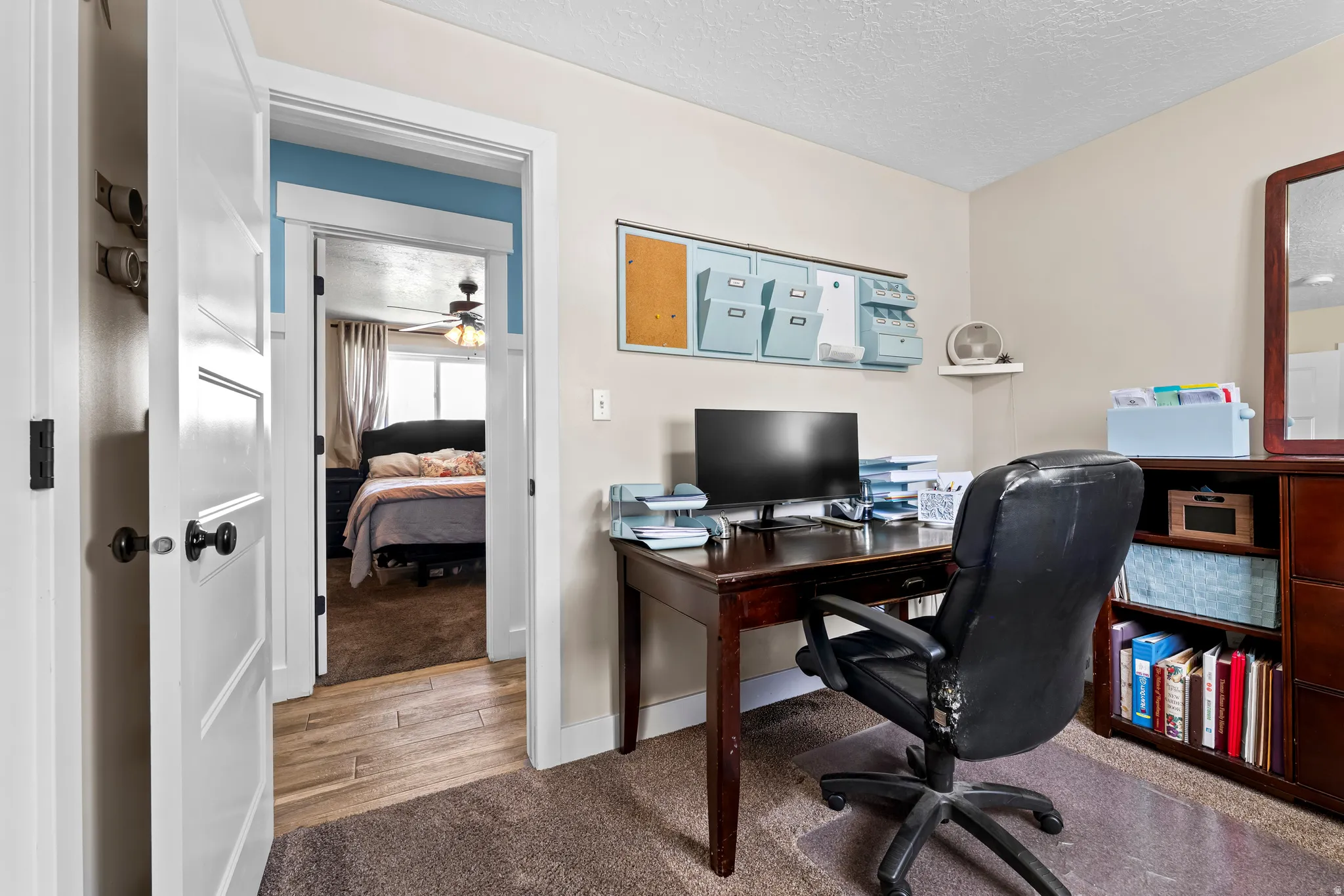 Office area featuring light carpet, a textured ceiling, light wood finished floors, and a ceiling fan