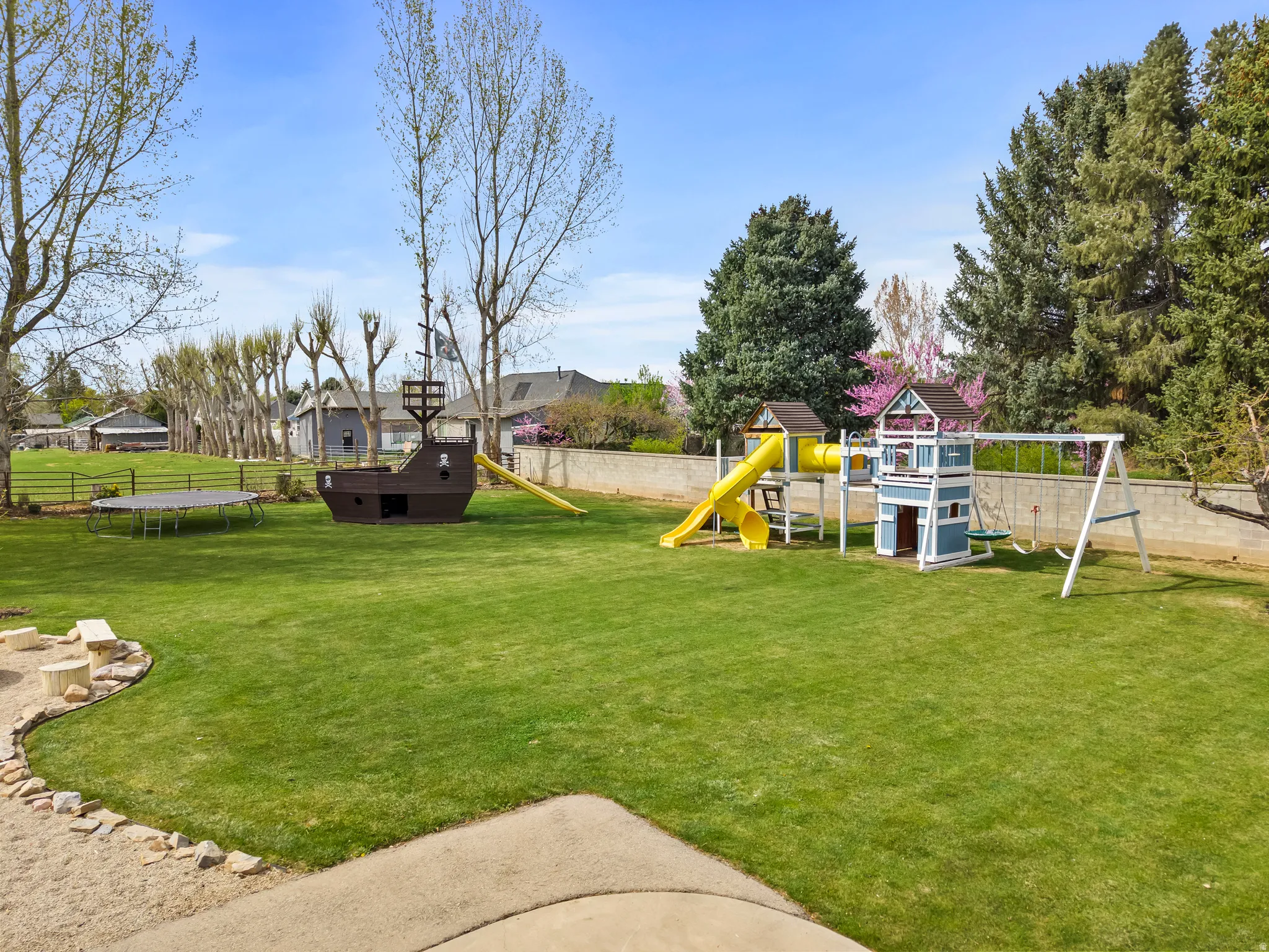 Fenced backyard with a trampoline and a playground