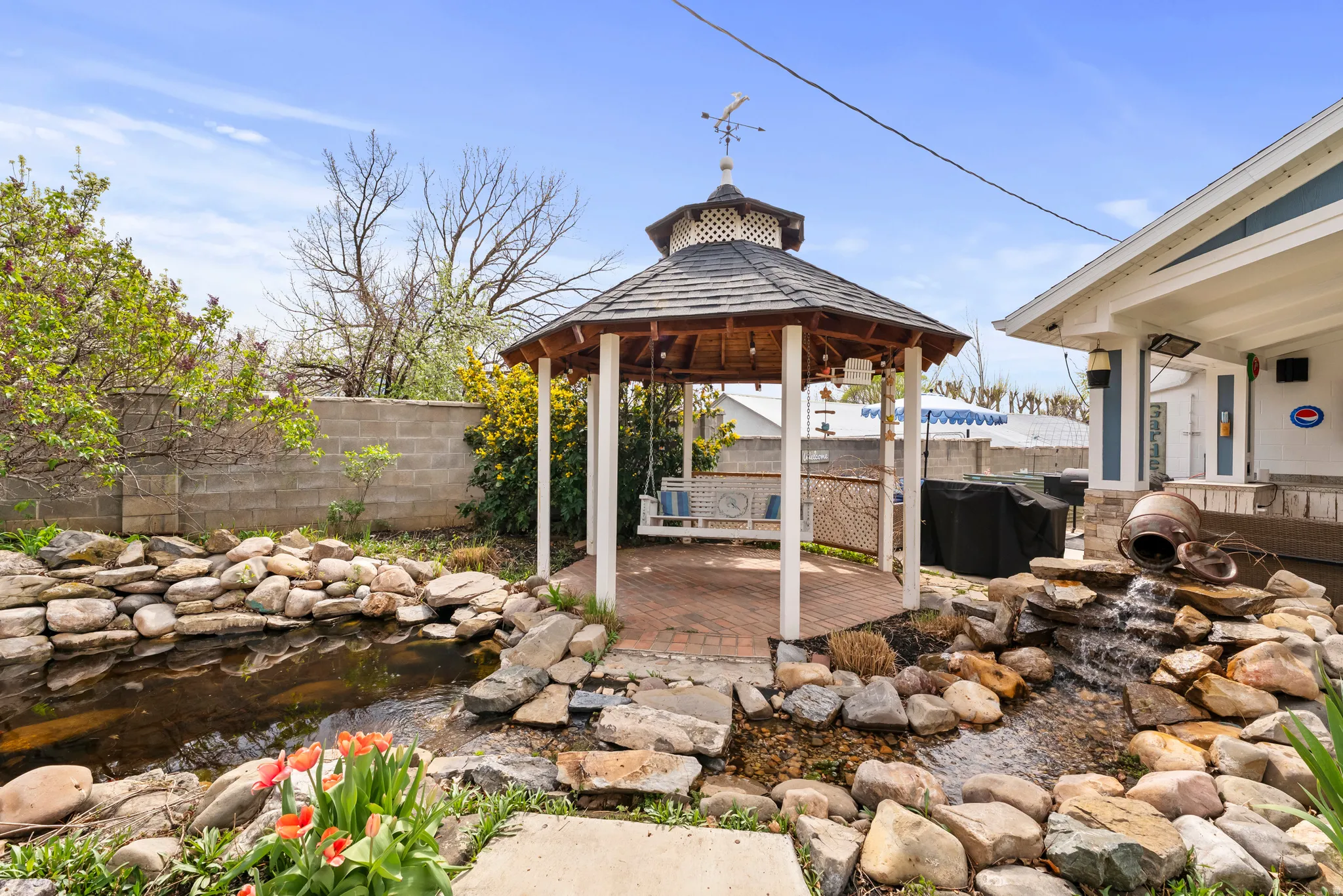 Fenced backyard with a gazebo, a patio area, a small pond, and grilling area