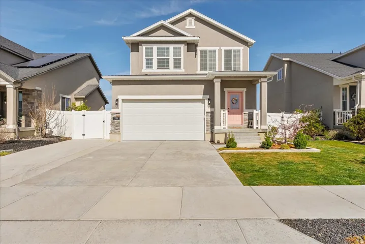 View of front facade with stucco siding, a gate, a porch, an attached garage, and concrete driveway