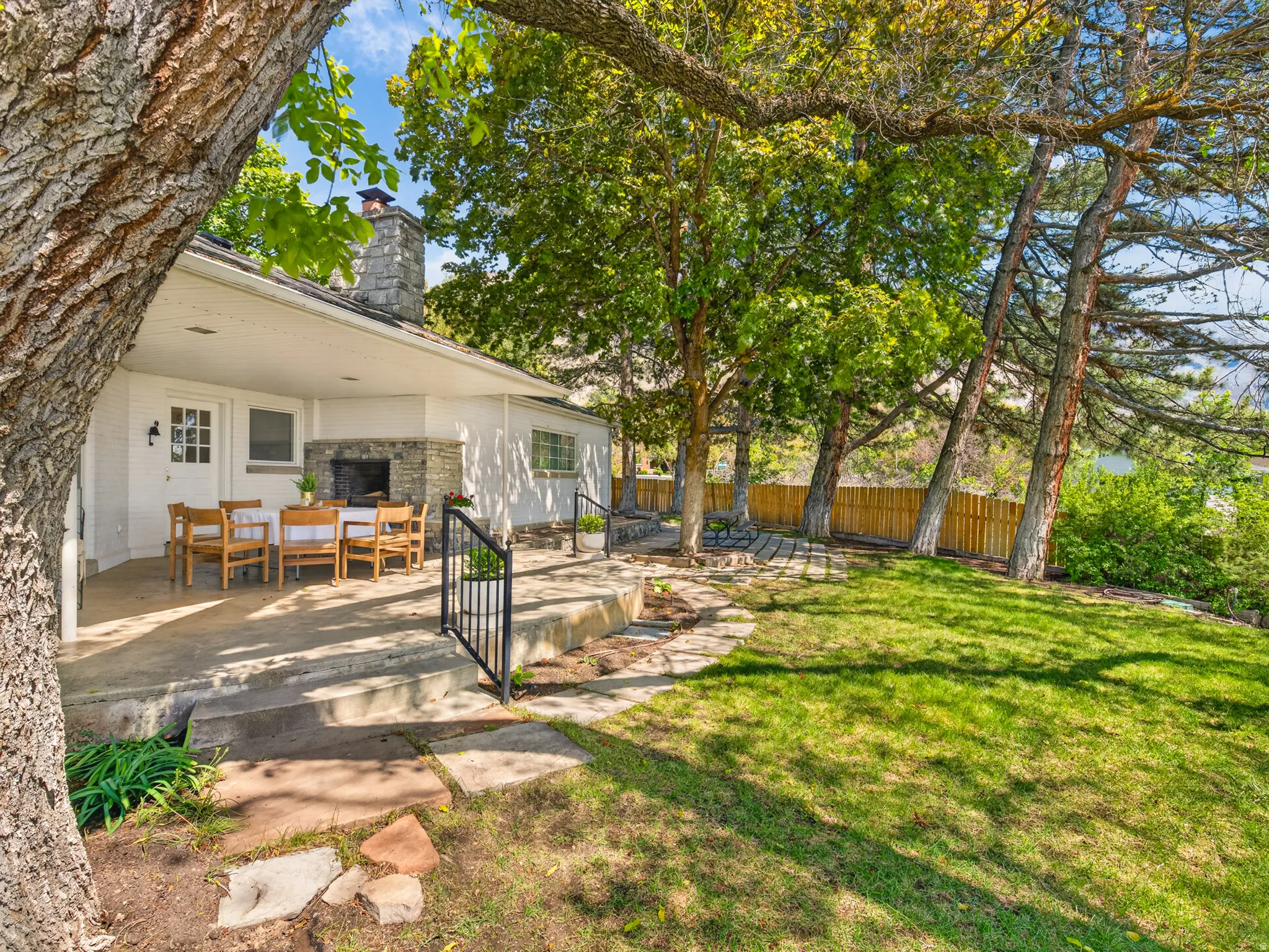 Expansive concrete patio featuring a stone fireplace and chimney