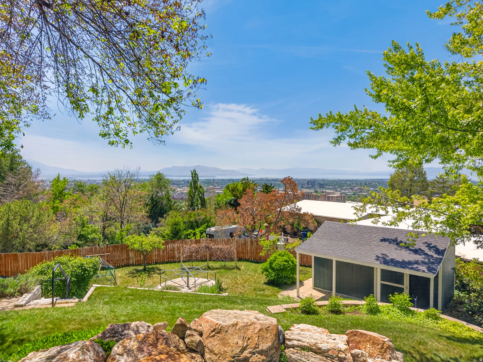 Expansive backyard featuring a manicured lawn, a detached shed, mature trees, and a wood fence