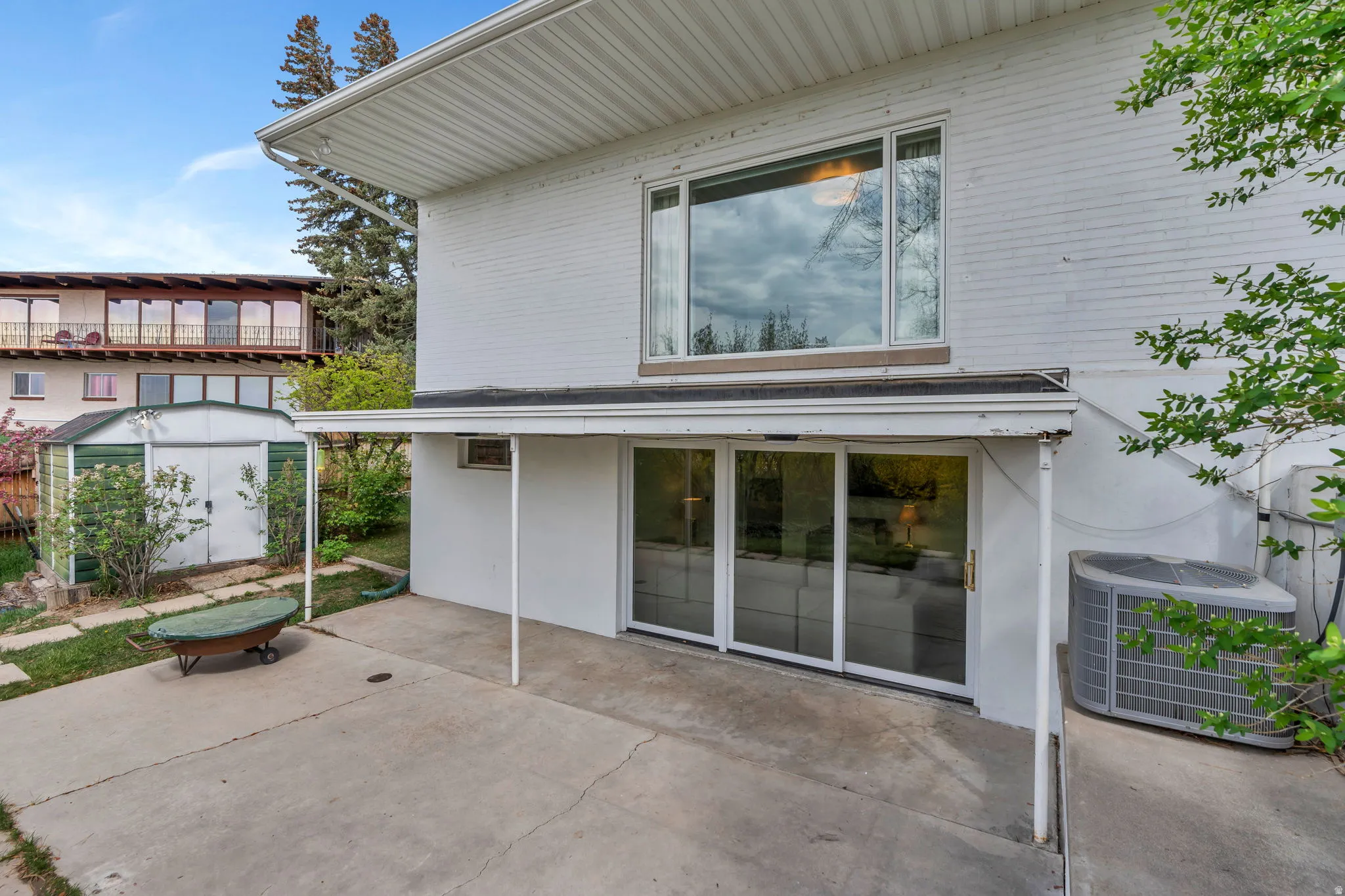 Rear view of property with a shed, a patio, and brick siding