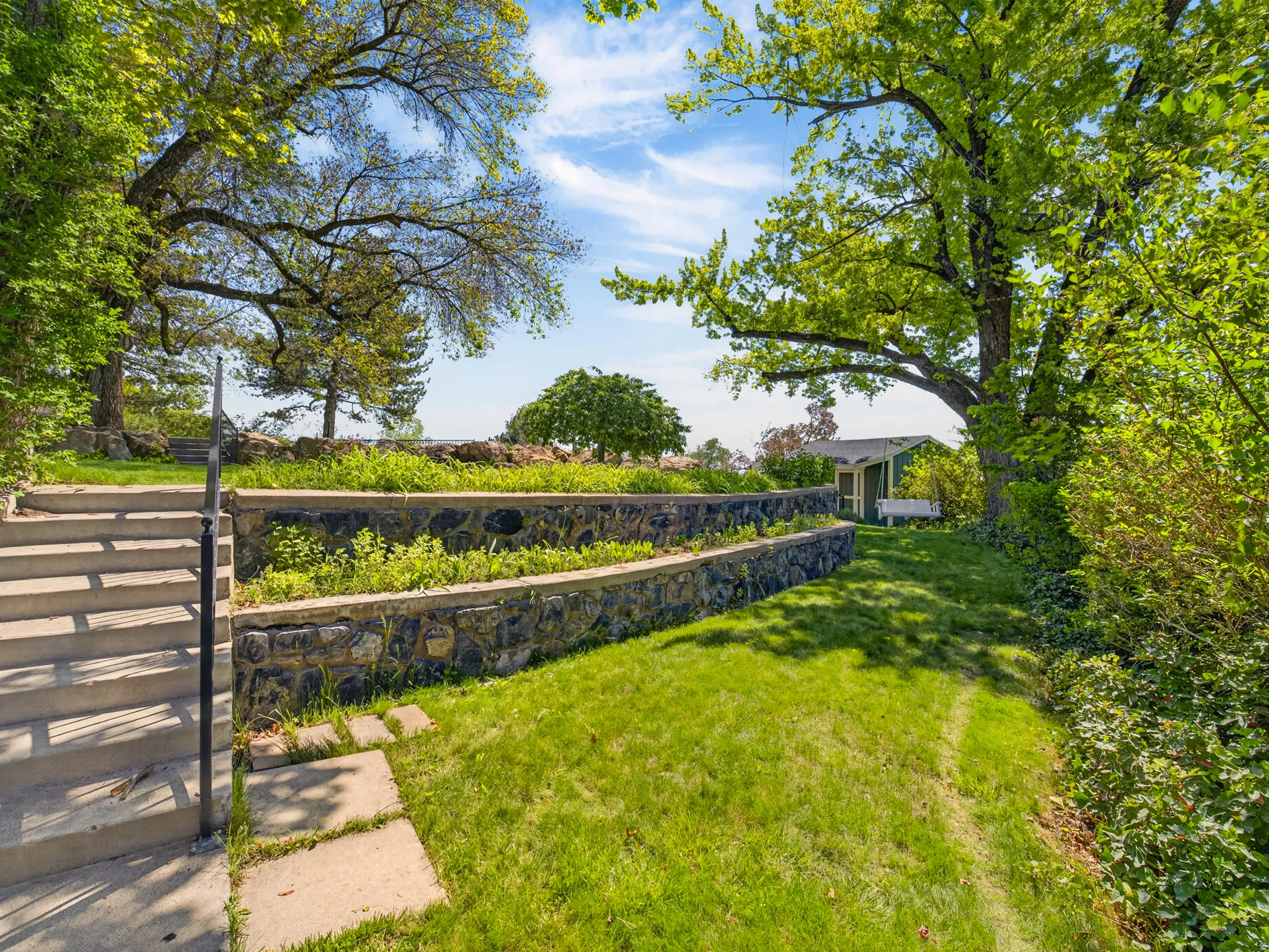 Terraced yard featuring expansive grass areas and mature trees