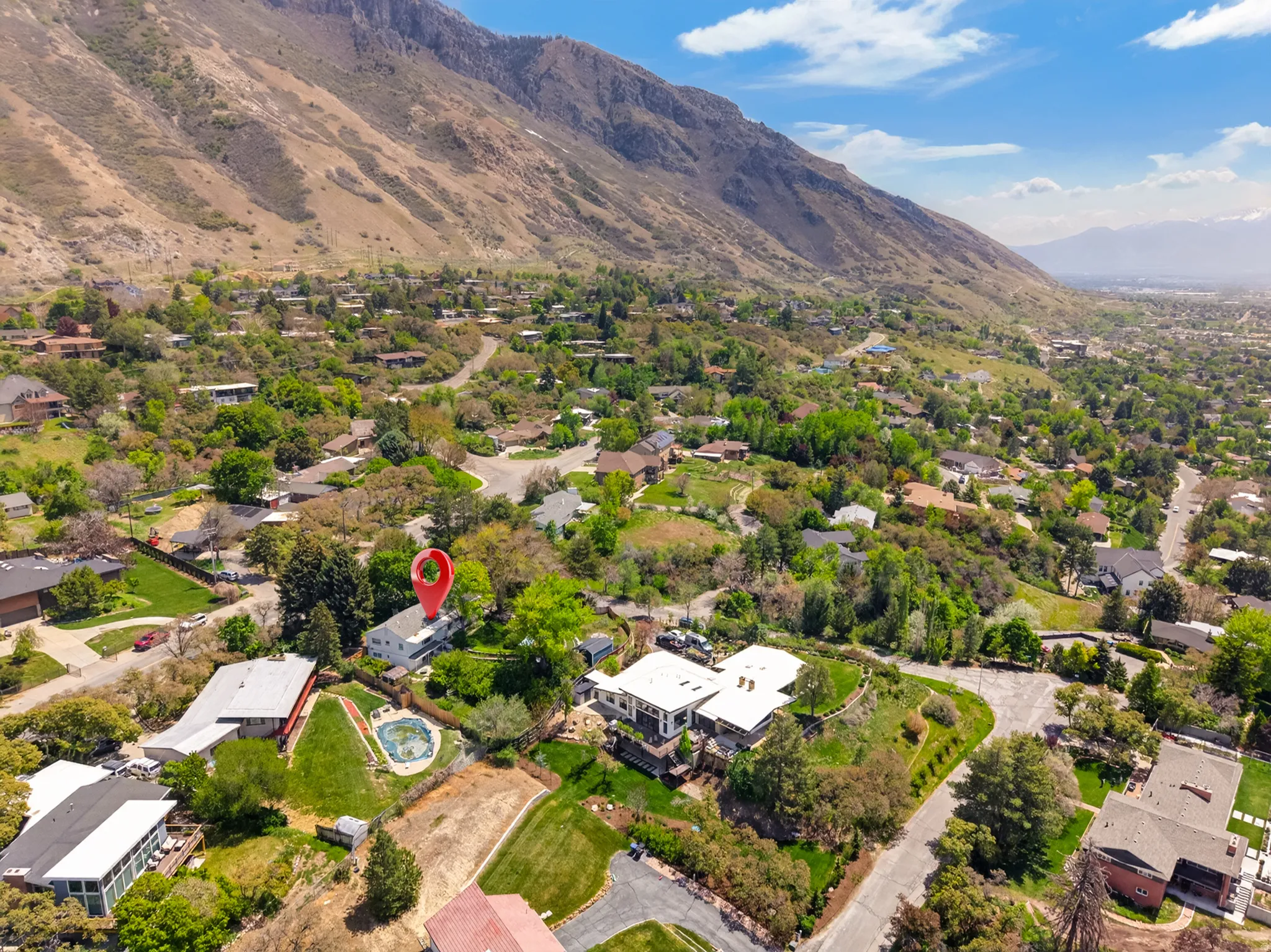 Hillside property featuring a residential structure and a swimming pool within a verdant neighborhood