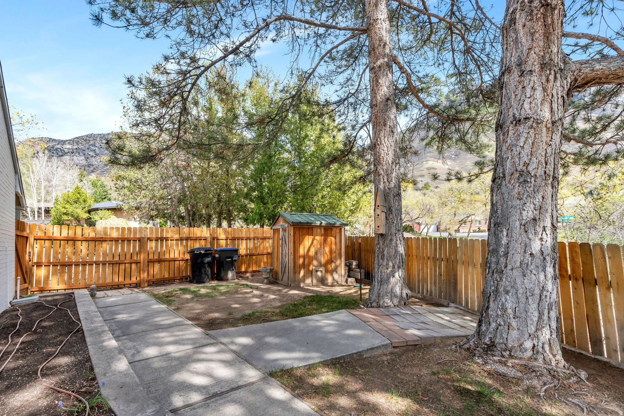 Fenced backyard with a storage unit and a mountain view